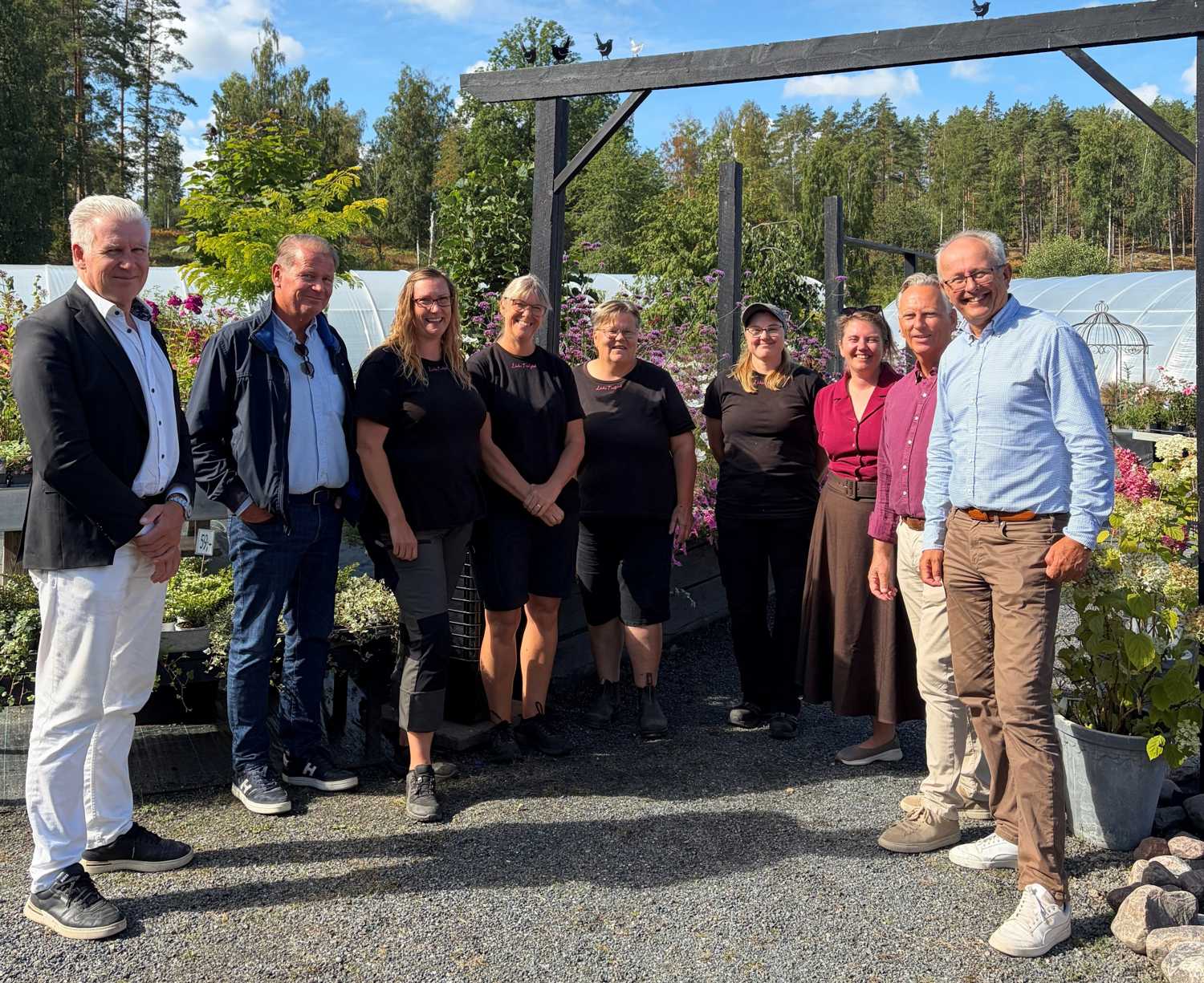 En grupp med människor som står framför Lindas trädgård.