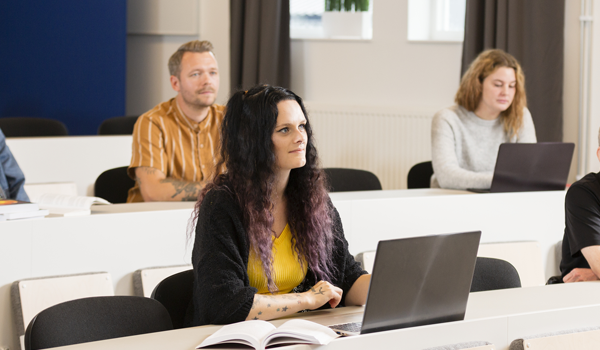 Studenter sitter i föreläsningssal och lyssnar på föreläsare.