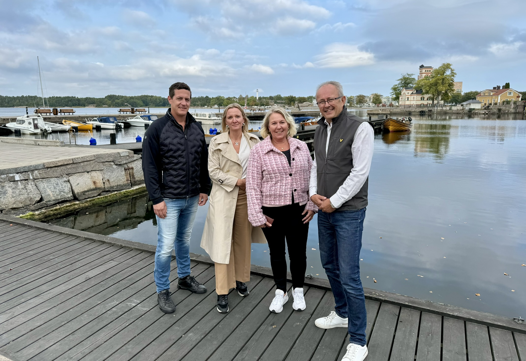 Fyra personer som står på en brygga med hamnen i Västervik bakom. 
