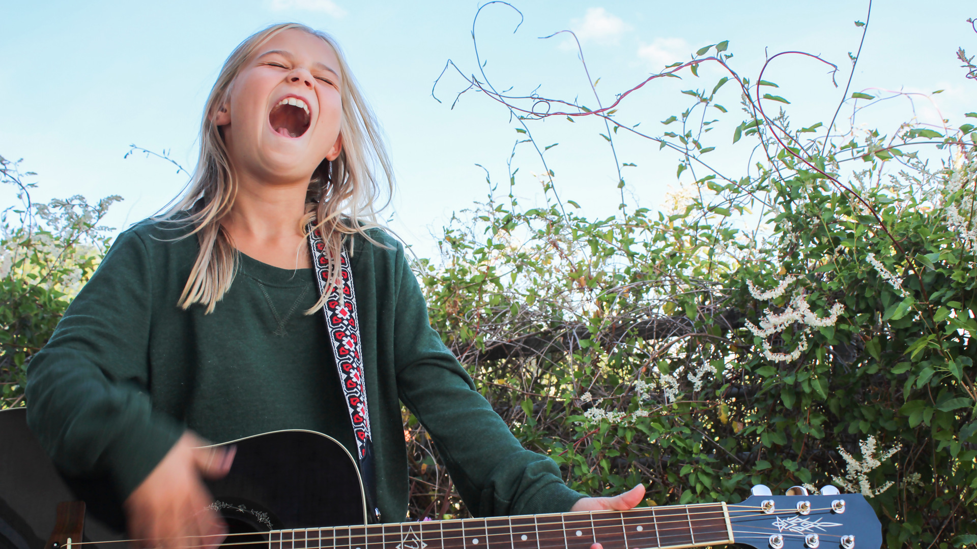 Ett barn med långt hår spelar gitarr