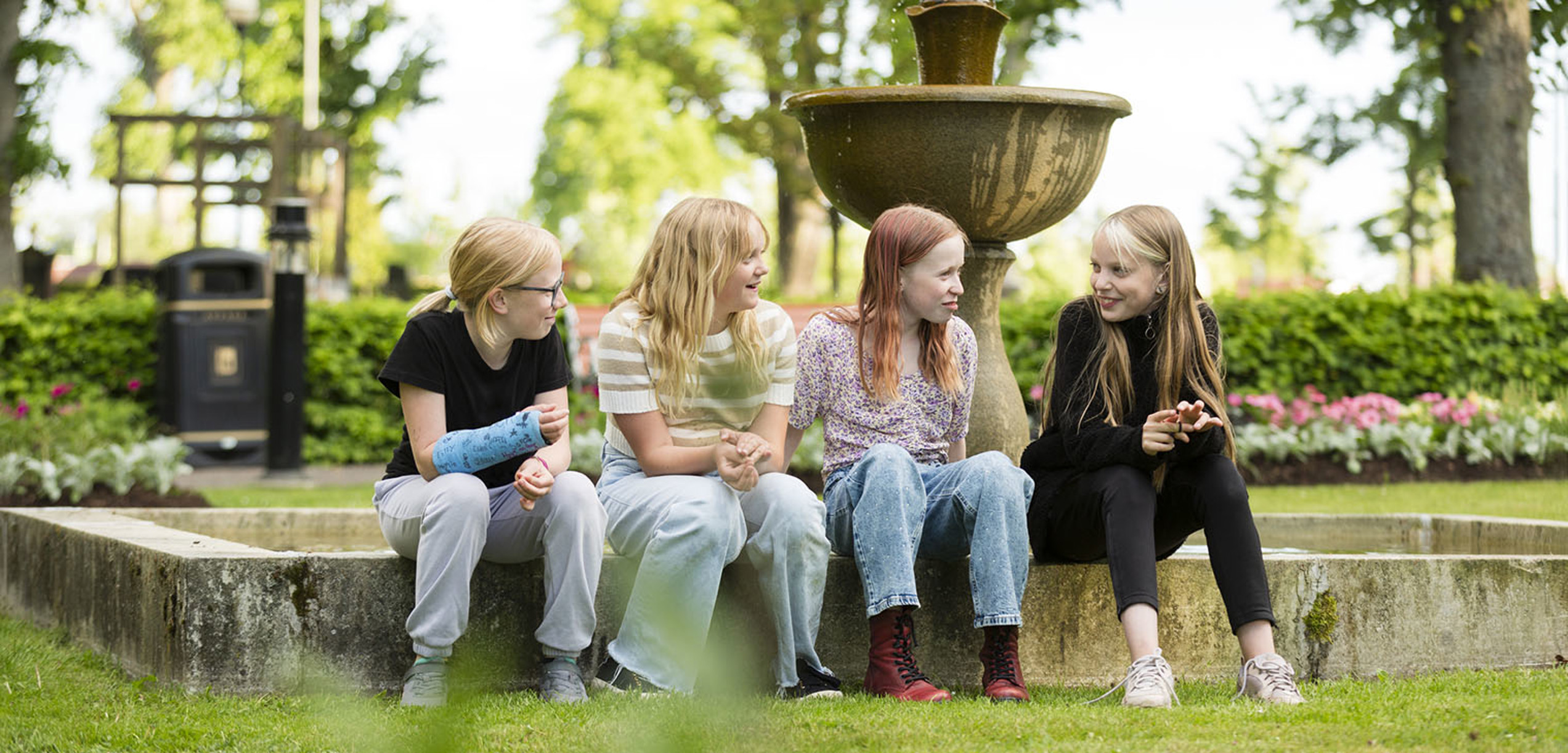 Barn i Stadsparken som sitter vid fontänen och skrattar.
