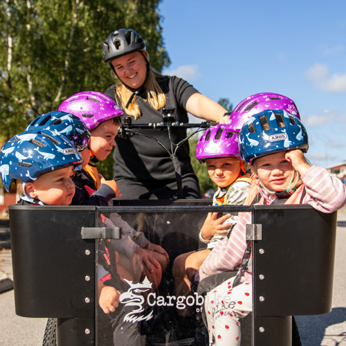 Lovisa som cyklar med barnen i lådcykel.