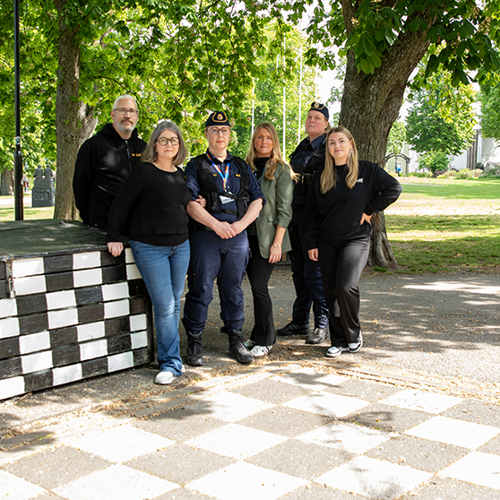 Gruppbild på polis, fältare, vuxna på stan, rektor och säkerhetssamordnare utomhus.