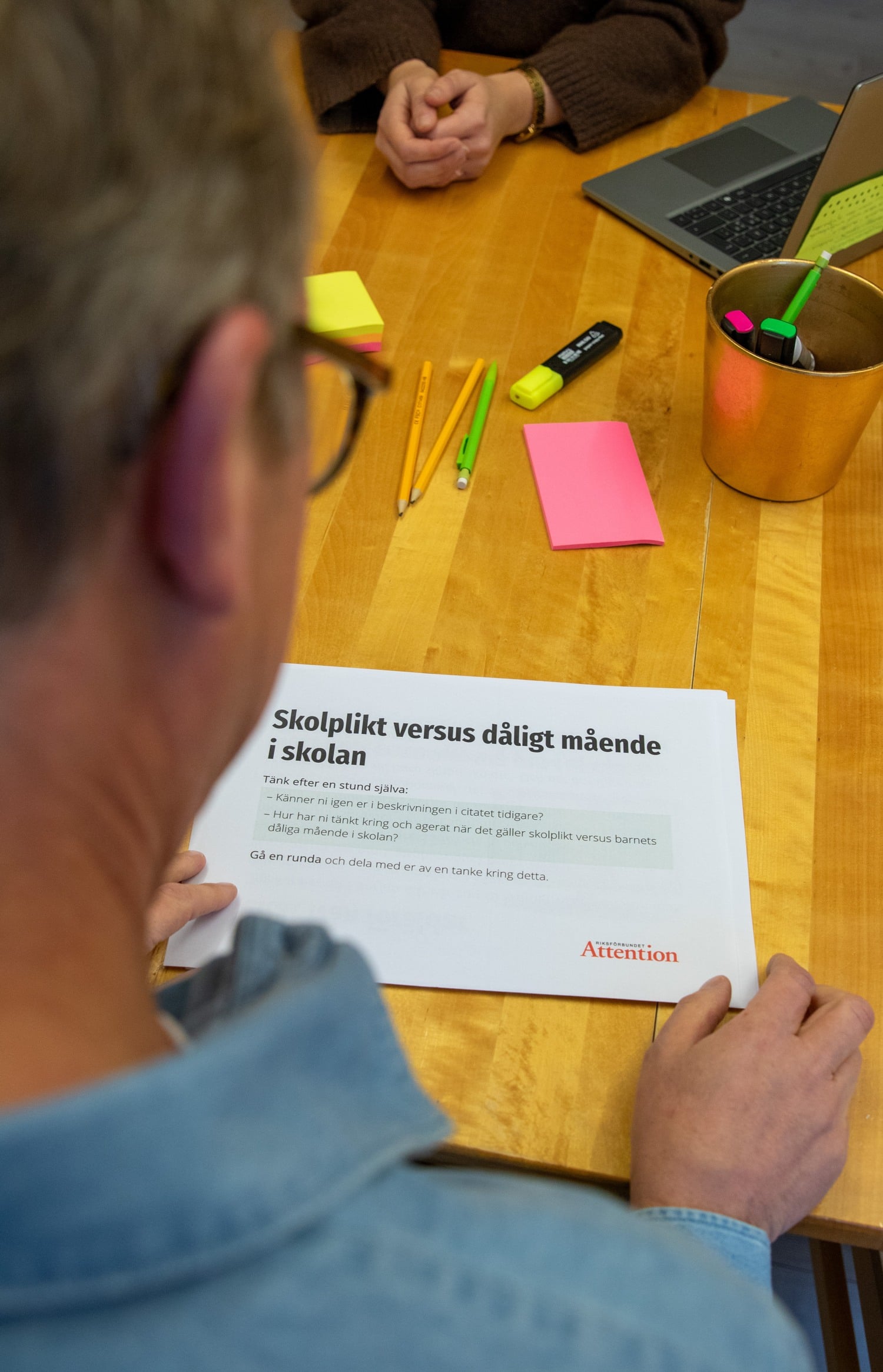 Fredrik tittar i materialet för träffarna med en sida uppe med rubriken: skolplikt versus dåligt mående". 