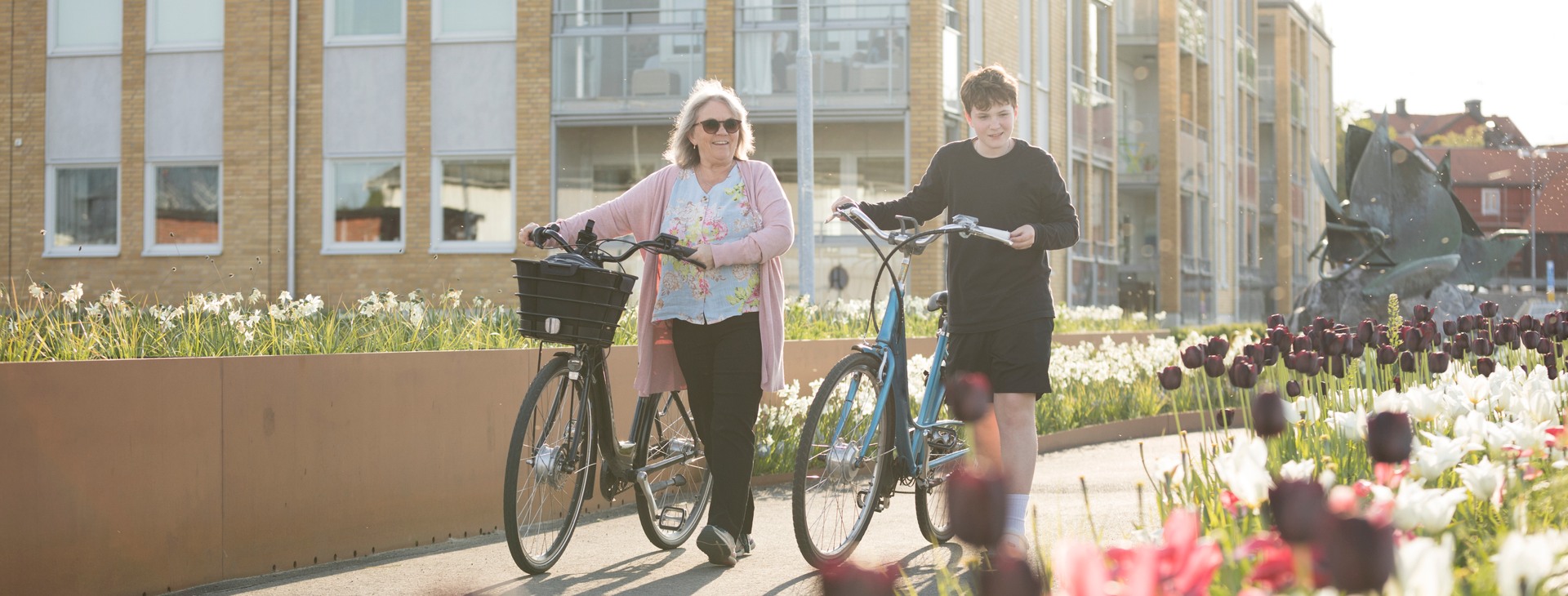 Kvinna och man som går med cyklar och pratar.