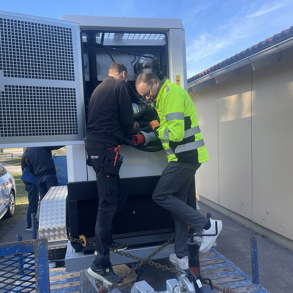 två personer arbetar med ett reservkraftverk